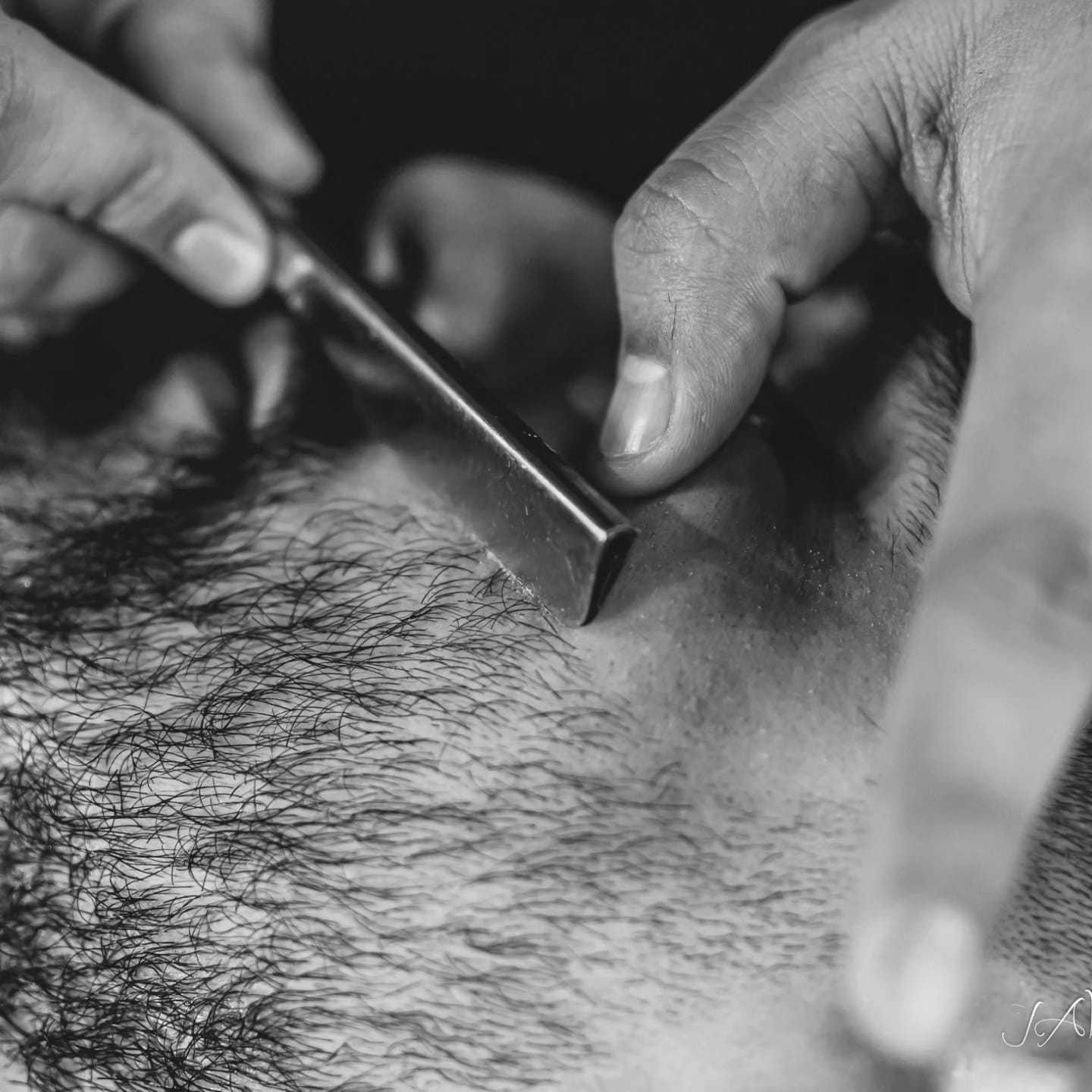 Close-up of a barber shaving a man's face with a straight razor.